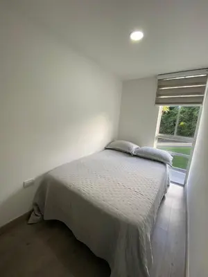 a white bedroom with a bed and a window at Moderno Apartamento Manizales in Manizales