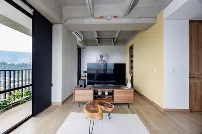 a living room with a television and a balcony at DISTRITO v in Estación El Salto