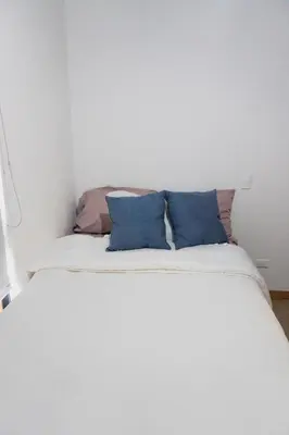 a white bed with blue pillows on top of it at Incredible new apartment in Envigado for six people in Envigado