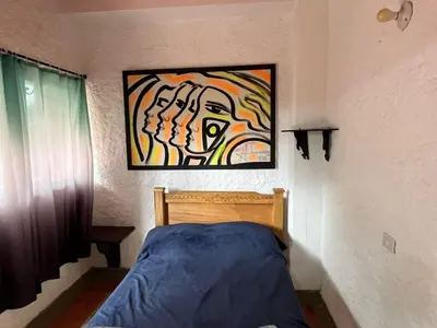 a bedroom with a bed with a painting on the wall at Hotel Montañitas in Guatapé