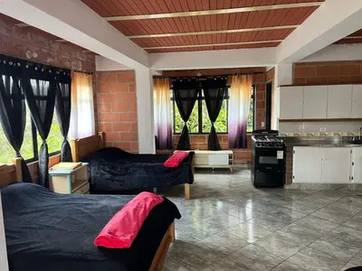 a room with two beds and a kitchen with windows at Hotel Montañitas in Guatapé