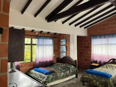 a bedroom with two beds and a window at Hotel Montañitas in Guatapé