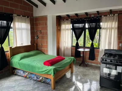 a bedroom with a bed with green sheets and a stove at Hotel Montañitas in Guatapé