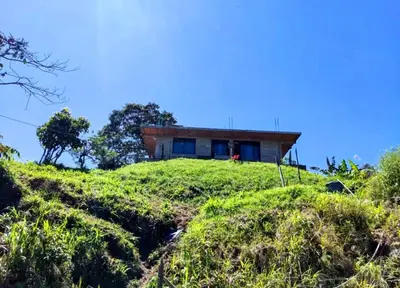 a house on top of a grassy hill at Casa Finca cerca al embalse Jaguas San Roque Antioquia