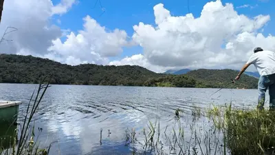 a man is standing on the shore of a lake at Casa Finca cerca al embalse Jaguas San Roque Antioquia