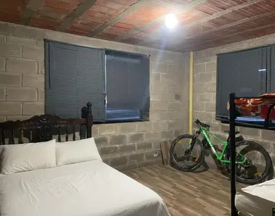 a bedroom with a bed and a bike in it at Casa Finca cerca al embalse Jaguas San Roque Antioquia