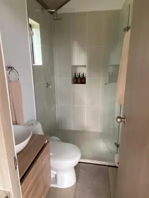 a bathroom with a toilet and a glass shower at Aluna's in Guatapé
