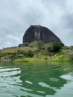 a large rock on a hill next to a body of water at Aluna's in Guatapé