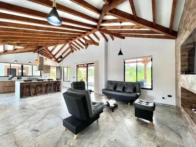 a living room with leather furniture and a kitchen at Casa Campestre de Lujo Familiar y Natural in Carmen de Viboral