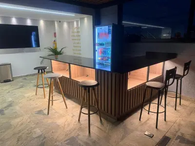 a bar with stools in a room with a television at loft 72 holiday inn medellin in Medellín