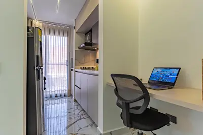 a desk with a laptop and a chair in a kitchen at loft 72 holiday inn medellin in Medellín