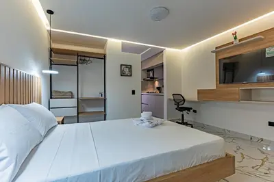 a bedroom with a large white bed and a kitchen at loft 72 holiday inn medellin in Medellín