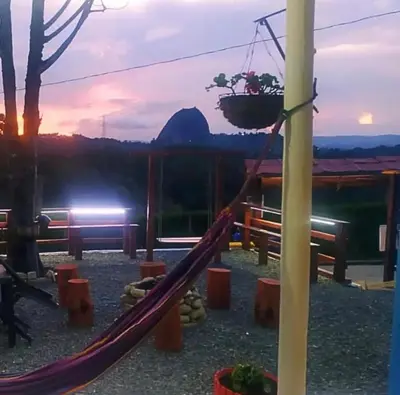 a resort with a hammock with a mountain in the background at Casa de Colores in Guatapé