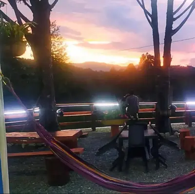 a person sitting in a hammock with a sunset in the background at Casa de Colores in Guatapé