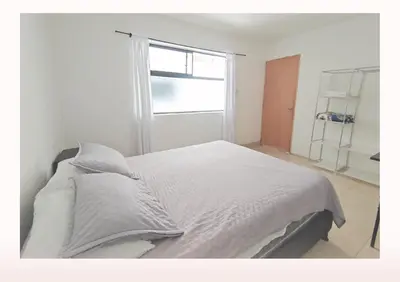 a bedroom with a white bed with a window at Hostal Casa Coliving Medellín - Laureles in Medellín