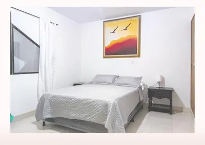 a white bedroom with a bed and a picture on the wall at Hostal Casa Coliving Medellín - Laureles in Medellín