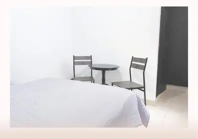a bedroom with a bed and two chairs and a table at Hostal Casa Coliving Medellín - Laureles in Medellín