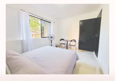 a bedroom with a white bed and a window at Hostal Casa Coliving Medellín - Laureles in Medellín