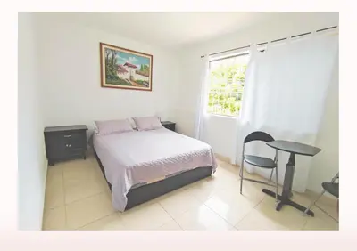 a bedroom with a bed and a table and a window at Hostal Casa Coliving Medellín - Laureles in Medellín