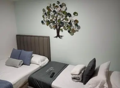 a bedroom with two beds and a tree on the wall at Ciudadela santafe La Margarita in Santa Fe de Antioquia