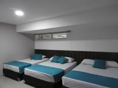 a room with three beds with blue pillows at Mediterraneo Express in Medellín