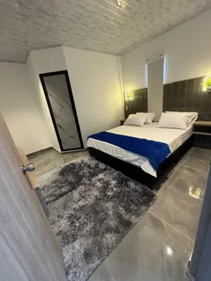 a bedroom with a large bed with a blue blanket at aparta hotel del toro in Puerto Triunfo