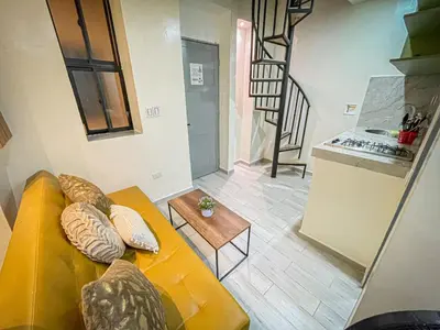 a living room with a yellow couch and a kitchen at la huerta de 1 alcoba in Medellín