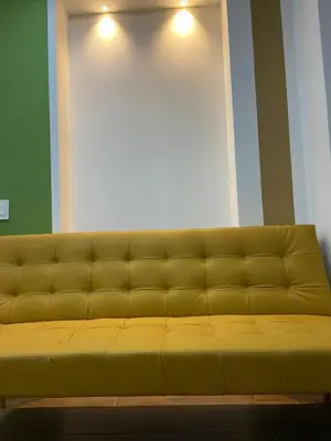 a yellow couch in a room with a wall at la huerta de 1 alcoba in Medellín