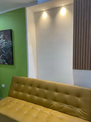 a brown couch in a room with a green wall at la huerta de 1 alcoba in Medellín