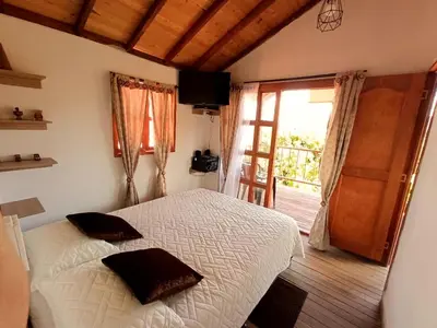 a bedroom with a bed and a door to a balcony at Cabaña Sensorial Vista y Silencio Total a 40 minutos de Medellín in San Vicente