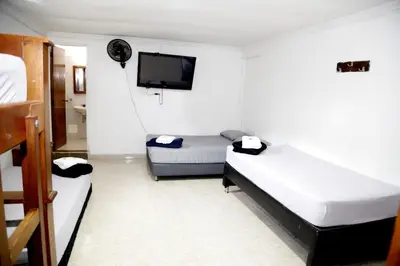 a room with two beds and a flat screen tv at Hotel Brisas del Atanasio in Medellín