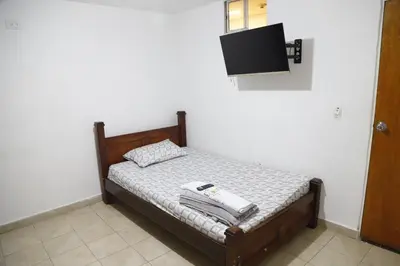 a bedroom with a bed with a tv on the wall at Hotel Brisas del Atanasio in Medellín