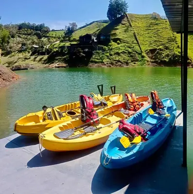 three yellow and blue boats are parked on a river at Agua Santa Ecolodge in Guatapé