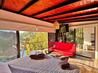 a bedroom with a bed and a red couch on a balcony at Agua Santa Ecolodge in Guatapé