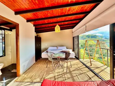 a room with a table and chairs on a balcony at Agua Santa Ecolodge in Guatapé