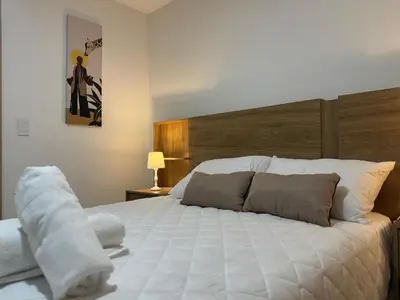 a bedroom with a large white bed with a wooden headboard at Aluna in Estación El Salto
