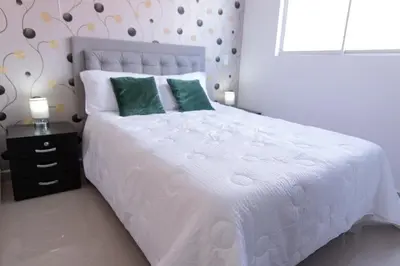 a bedroom with a white bed with green pillows at 504-Apartamento 3BR a Pasos del Parque de Sabaneta in Sabaneta