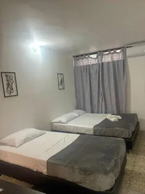 two beds in a room with a window at Absolute Nova Hotel in Medellín