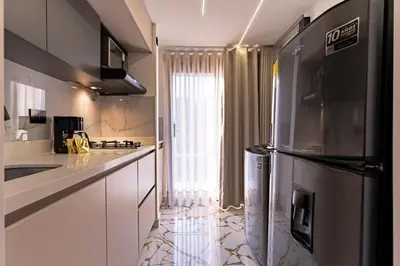 a kitchen with white cabinets and a stainless steel refrigerator at Exclusivo Urban Loft en Laureles in Medellín