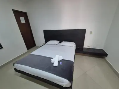 a bedroom with a large bed with white sheets at hotel universo plaza in Medellín