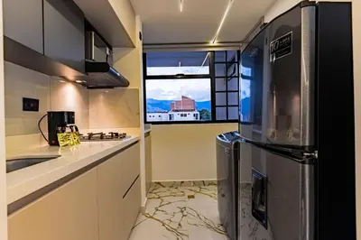 a kitchen with a refrigerator and a window at apartaloft laureles 70 in Medellín