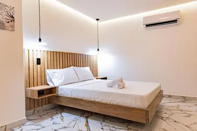 a bedroom with a bed with white sheets and a wooden wall at apartaloft laureles 70 in Medellín