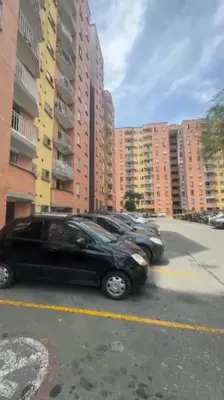 two cars parked in a parking lot next to tall buildings at Camino de los Vientos in Bello