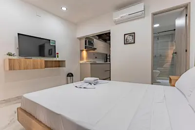 a white bedroom with a large bed and a tv at Fountain Loft 72 in Medellín
