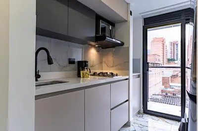 a kitchen with white cabinets and a sink and a window at Apartaloft exclusivo en laureles in Medellín