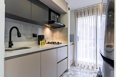 a kitchen with white cabinets and a sink and a window at Apartaloft exclusivo en laureles in Medellín