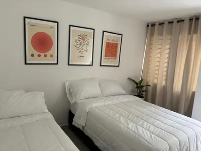 a bedroom with two beds and three pictures on the wall at El hospedaje de Ana in Medellín