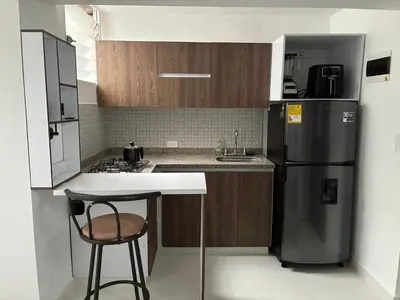 a kitchen with a refrigerator and a table and a stool at El hospedaje de Ana in Medellín