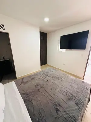a bedroom with a bed and a flat screen tv on the wall at Studio apartment in Laureles, ideal central location in Medellín