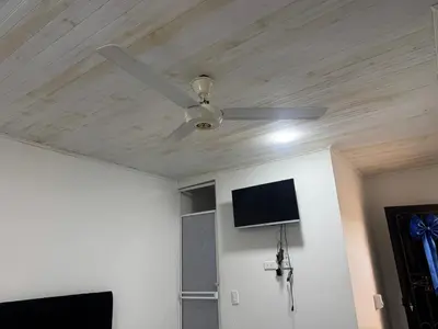 a ceiling fan in a room with a tv at Lucena place in La Dorada